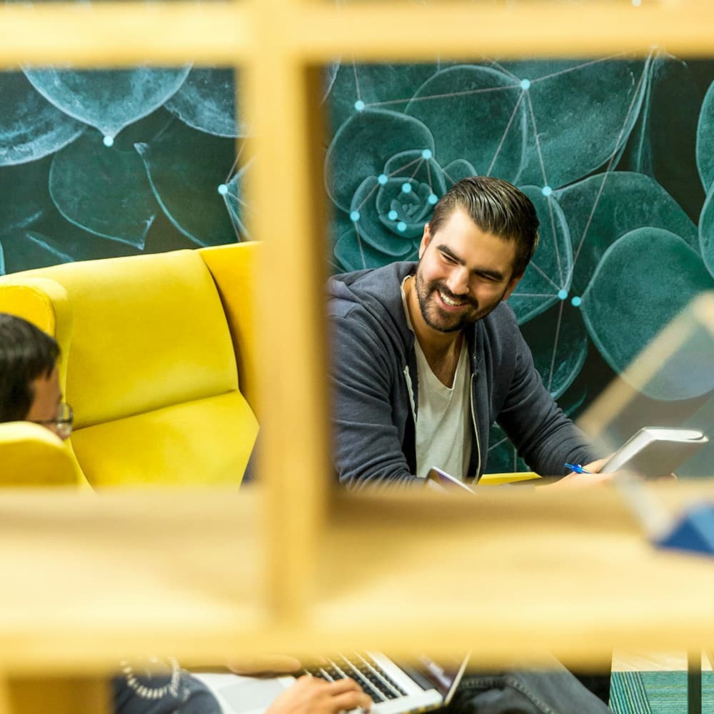 Casual man smiling with notebook, view through window pane