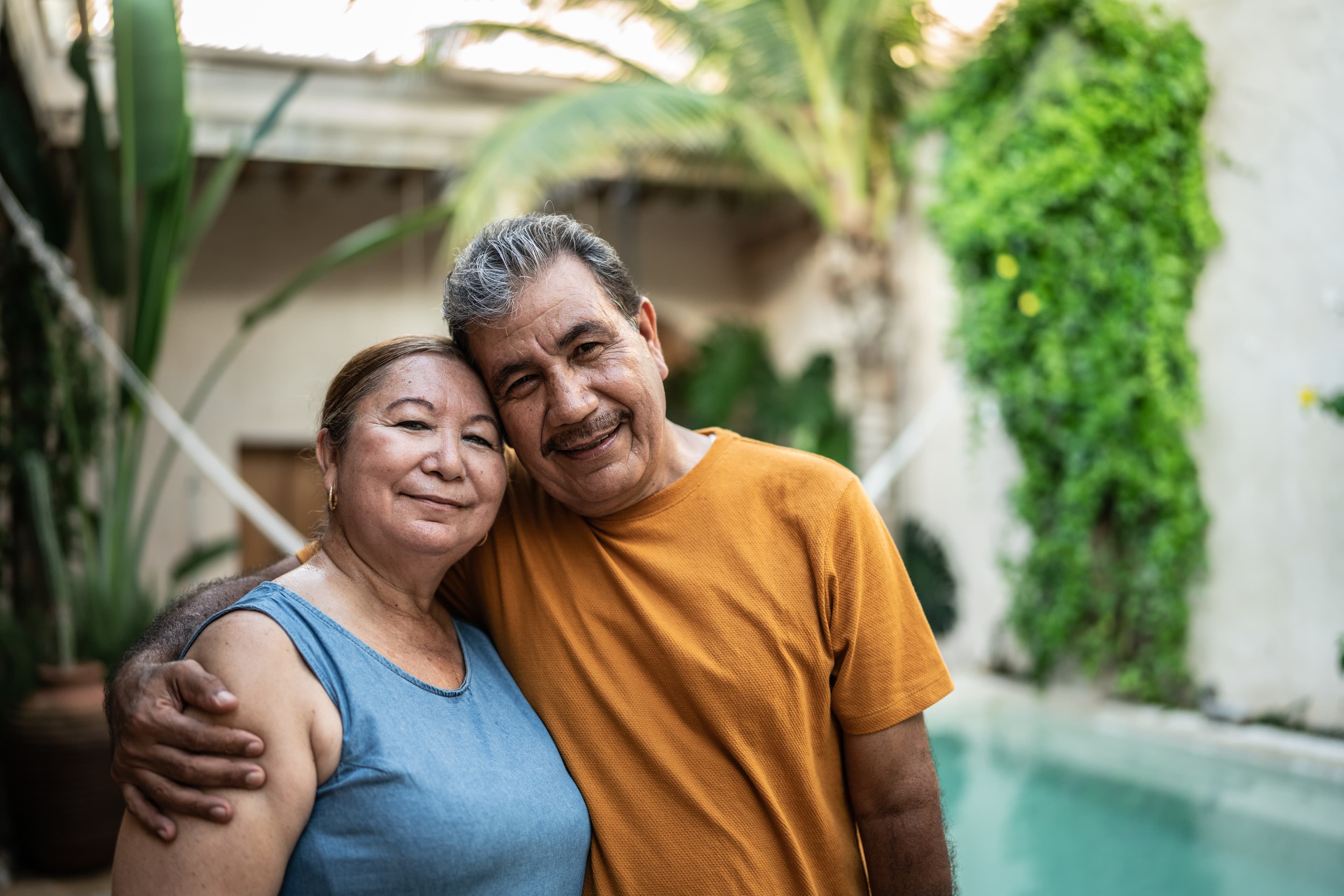 Happy senior couple standing in front of their home
